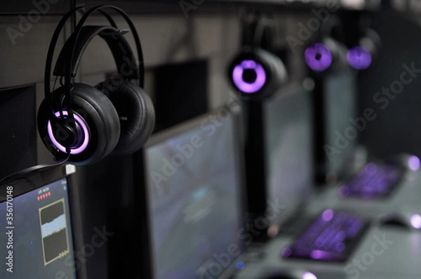 Fototapeta Professional gaming headphones with bright side led lights hanging off the monitor.