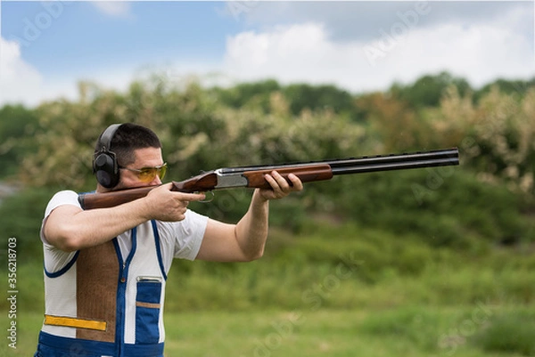 Fototapeta Man shooting skeet with a shotgun. Skeet shooting, trap shooting.