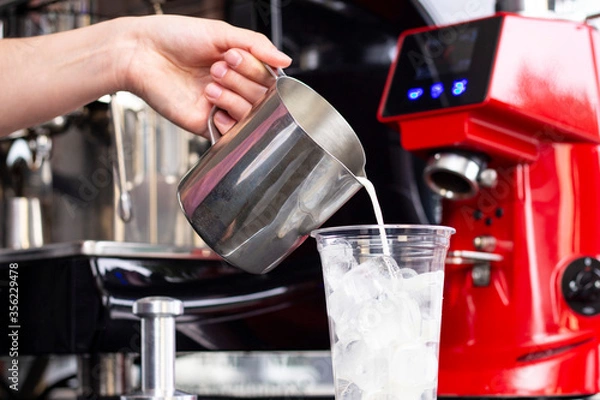 Fototapeta Ice coffee preparation preparation service concept. Barista makes espresso in a cafe; close-up of milk pouring. Freshly ground coffee close-up