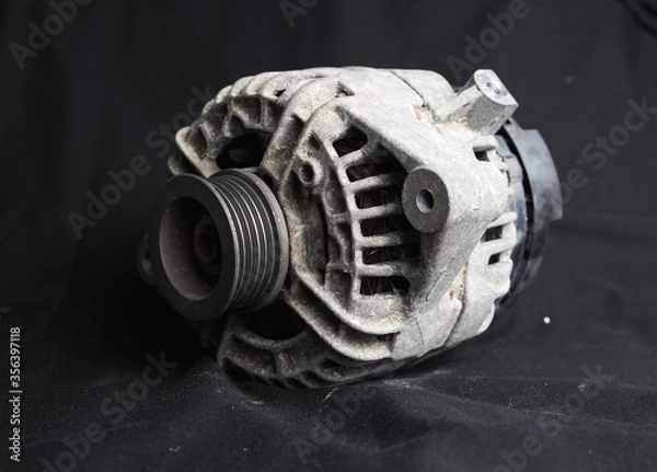 Obraz Used, dirty unclean alternator car part shot on a black background to highlight the silver metal piece of a car taken to be replaced with a brand new part. Pulley an electric parts discarded rubbish