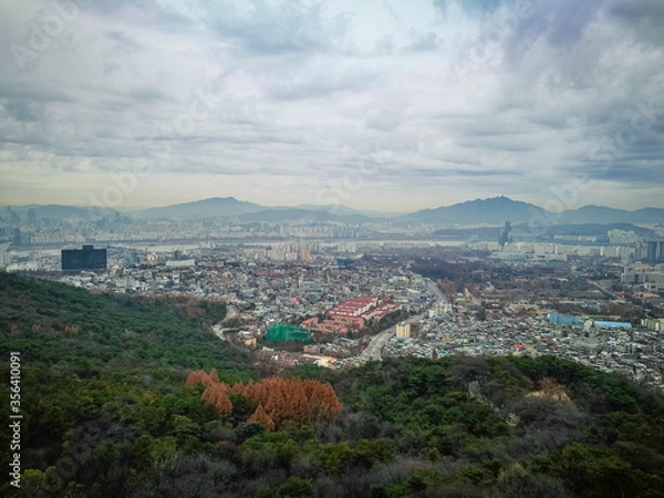 Fototapeta Bird eye view of part of capital city of Seoul from high ground at namsan Seoul South Korea. Visible noise and soft focus due to foggy and cloudy morning. Cloudy blue sky at background.