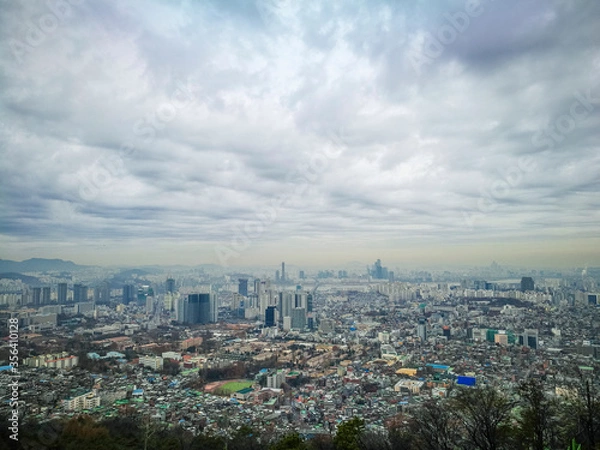 Fototapeta High angle view of part of capital city of Seoul from high ground at namsan Seoul South Korea. Visible noise and soft focus due to foggy and cloudy morning. Cloudy blue sky at background.