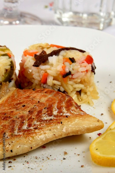 Fototapeta colorful rice with vegetables and fried fish on a white plate