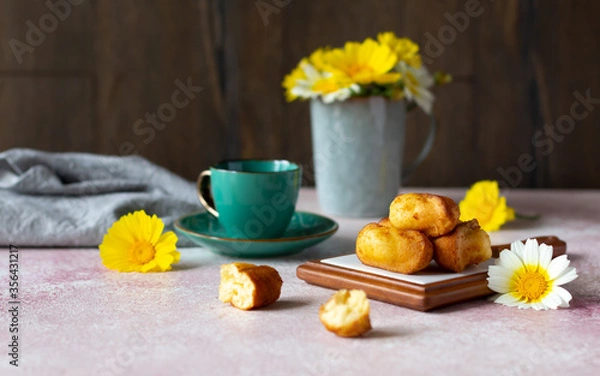 Obraz A cup of coffee or tea with small sponge biscuits, traditional French madeleines cakes, white and yellow wildflowers on the table