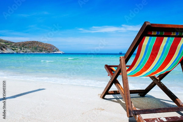 Fototapeta Beach chairs on a sandy beach by the ocean, the concept of relaxation, traveling on a tropical island, relaxation with beautiful views of the bruise sea and blue sky