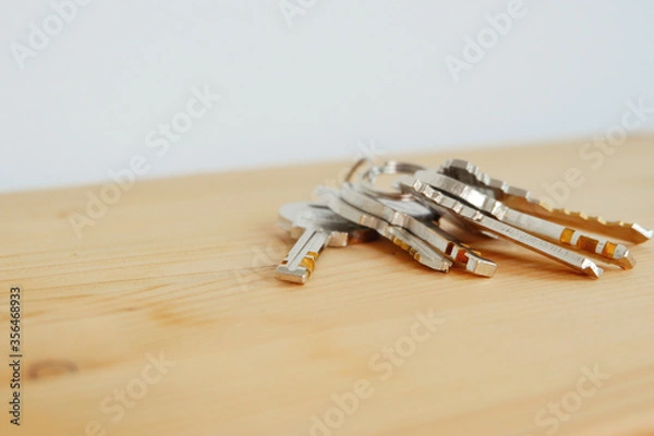 Fototapeta Bunch of keys on a shaped keychain at wooden table background. Concept for real estate or renting home with copy space,Close up.
