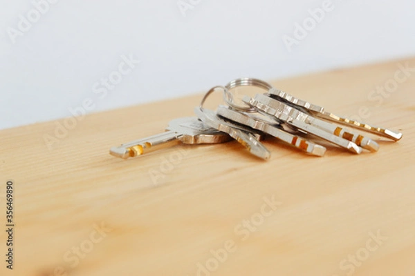 Fototapeta Bunch of keys on a shaped keychain at wooden table background. Concept for real estate or renting home with copy space,Close up.

