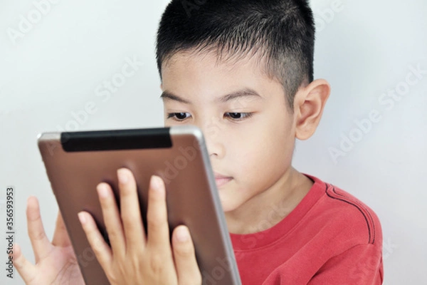 Obraz A boy playing a tablet on a white background