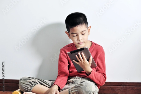 Obraz A boy playing a tablet on a white background