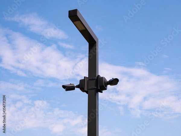 Fototapeta Outdoor surveillance video cameras on street lamp against blue sky with copy space for text. Security concept.
