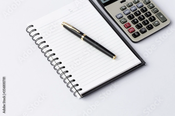 Fototapeta Pen, calculator on notebook close up on white background