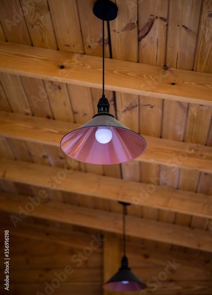 Obraz round metal chandelier on the wood ceiling