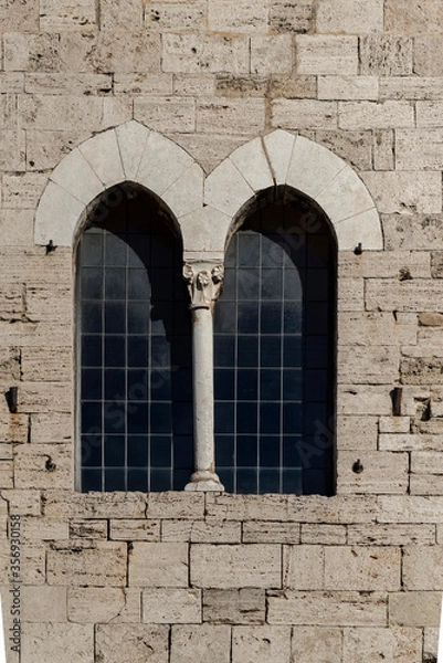 Fototapeta Medieval window, double lancet window, two windows separated by column and capital, vertical photo front view, background white stone masonry
