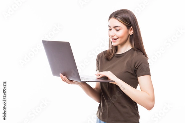 Fototapeta Portrait of a smiling girl holding laptop isolated on a white background and looking at camera