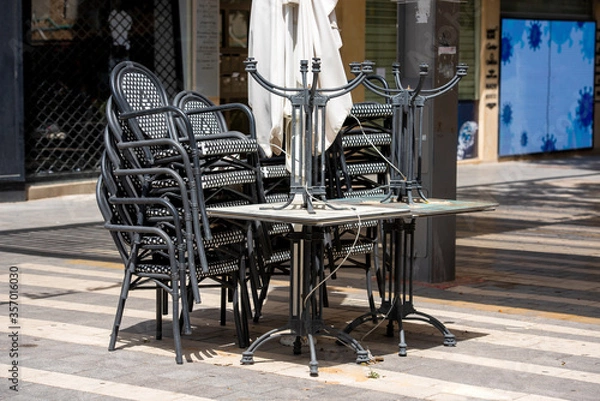 Obraz folded tables and chairs in a closed street cafe