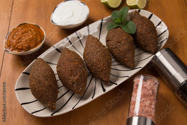 Fototapeta fried kibbeh served with yogurt sauce, and pepper sauce, on a plate