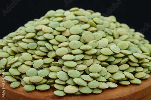 Fototapeta Green lentils in pottery bowl on black background