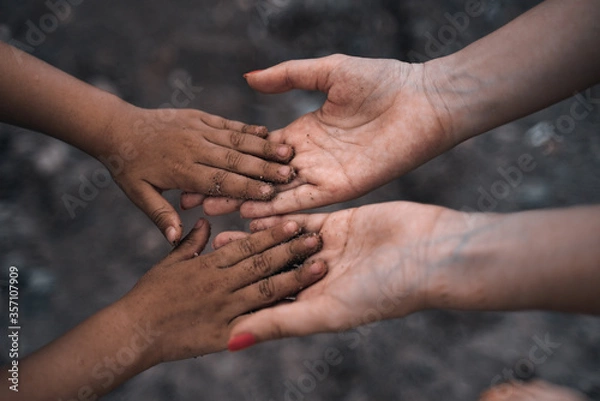 Fototapeta The girl holds in her hands the hands of a child. International family. Help to refugees. Social problems of children. 