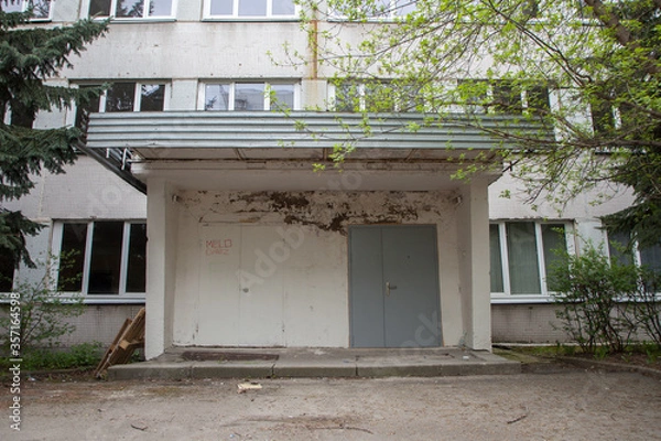Obraz Entrance to the building in the trees, an old brutal building
