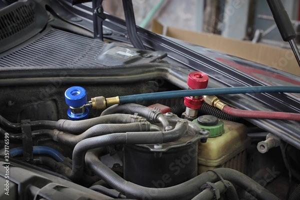 Fototapeta Charging of air condition unit at modern car, closeup of equipment conected to car engine, red and blue clutch couplings