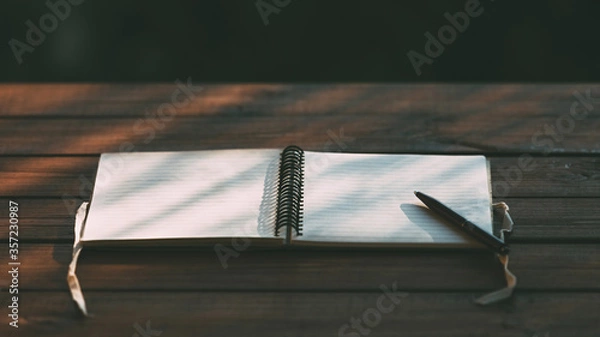 Fototapeta An open paper notebook with ribbons and a pen for writing planning on a textured wooden table