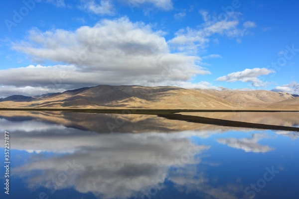 Fototapeta Beautiful reflection of hills and clouds in glass like waters of lake in Tibet, Asia