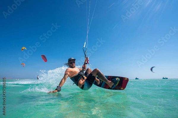 Fototapeta kiter does a difficult trick on a background of transparent water and blue sky