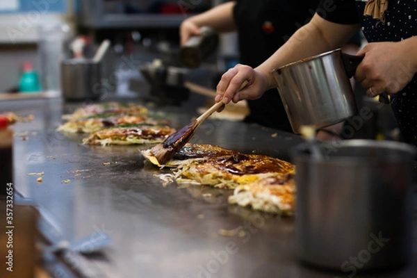 Obraz Making a Hiroshima style layered pancake, Okonomiyaki on a hot pan.