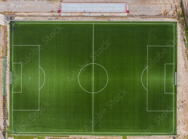 Fototapeta Top down drone view of a football field on the outskirts of a village