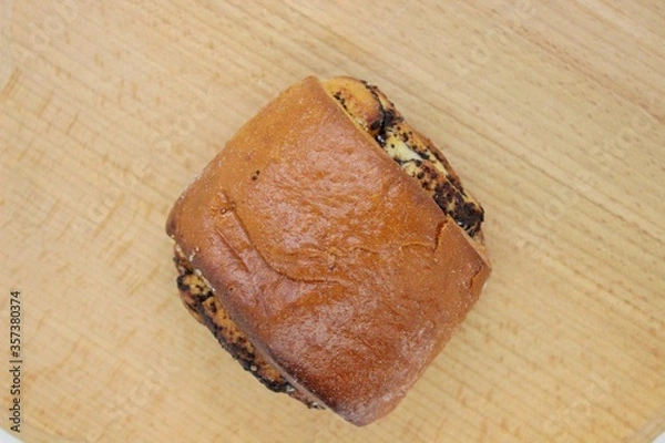 Obraz Beautiful delicious bun with poppy seeds located on a wooden surface