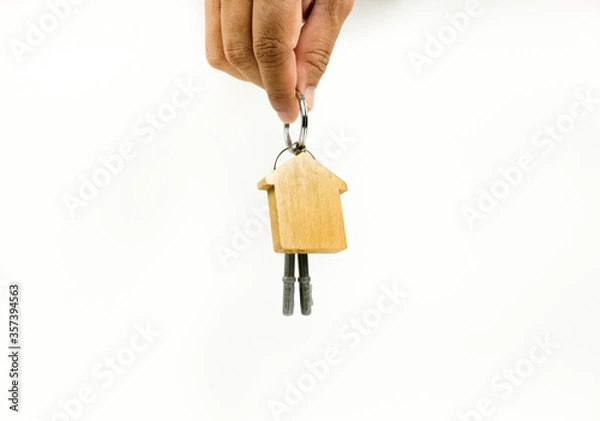 Fototapeta Conceptual image of house keys hand-over after completed home financing process. Keys with wooden key chain change hands. Blank space for texts. Focus on wooden keys; other on gradient blur.