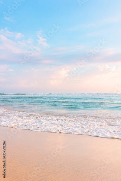Fototapeta Sandy beach, blue cloudy sky and soft ocean wave with warm sunset light.