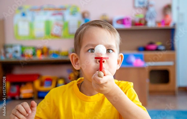 Obraz The little boy in the classroom with the speech therapist . The use of special tools for speech correction.
