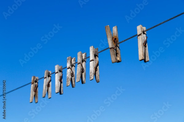 Obraz clothespin for drying clothes on a rope in different positions against a blue sky