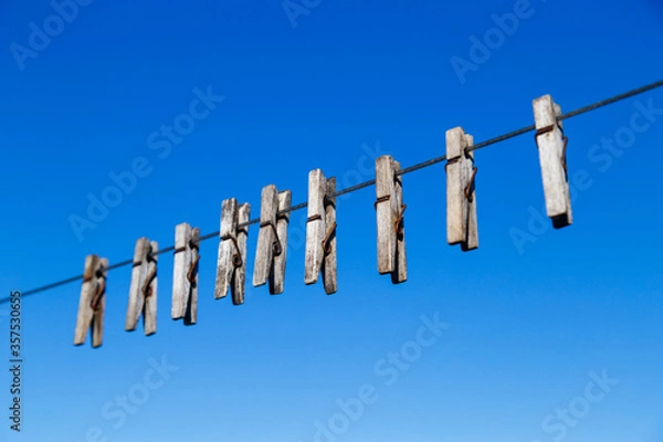 Obraz clothespin for drying clothes on a rope in different positions against a blue sky