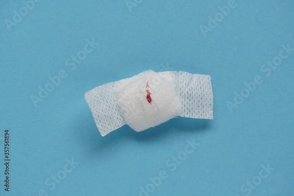 Fototapeta Blood tests, small trace of blood on bandage with band-aid on blue background. Coronavirus test. blood draw