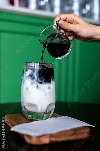 Fototapeta Iced coffee mixed with milk together served in a glass on wood