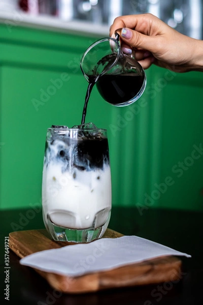 Fototapeta Iced coffee mixed with milk together served in a glass on wood