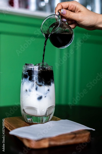 Fototapeta Iced coffee mixed with milk together served in a glass on wood
