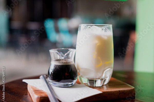 Fototapeta Coffee and milk in a glass, add ice, prepare to pour together to mix.