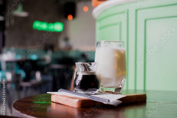 Fototapeta Coffee and milk in a glass, add ice, prepare to pour together to mix.