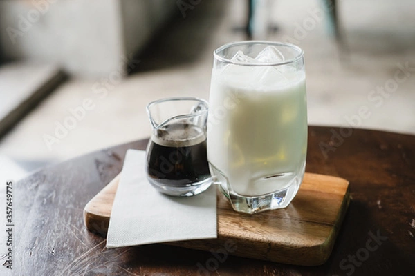 Fototapeta Coffee and milk in a glass, add ice, prepare to pour together to mix.