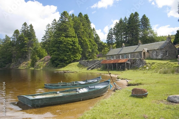 Obraz Two fishing boats moored by a row of old fishing lodges 
