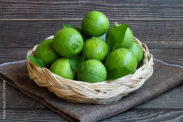Obraz Natural fresh lime in basket on wooden background.