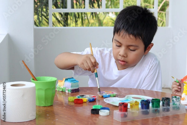 Obraz Cute little boys painting Plaster doll at the table with art supplies.