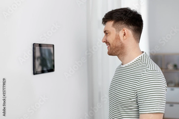 Fototapeta automation, internet of things and technology concept - happy smiling man looking at tablet pc computer at smart home