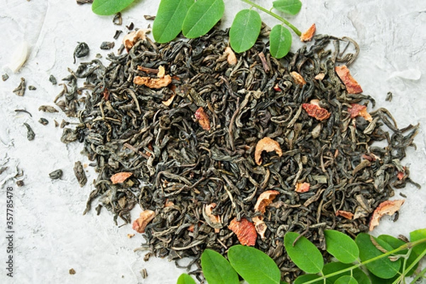 Fototapeta dried tea leaves with berries and fresh green leaves on a white cement background