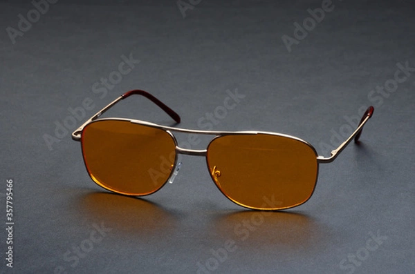 Obraz Yellow glasses on a black background. Anti-glare glasses for the driver in a metal frame with yellow glasses on black background. Front view.