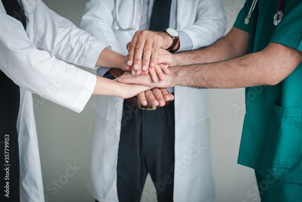 Fototapeta Medical Doctors Team Stacking Their Hands Together, Closeup of Professional Physician Doctor Join Hand for Unity and Support Togetherness in Hospital. Medicine Healthcare/Collaboration Union Concept