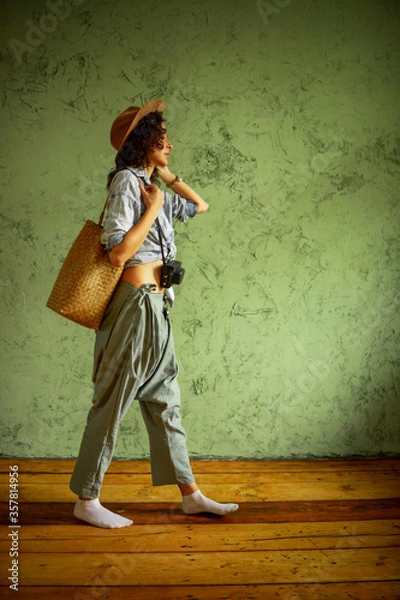Fototapeta Tourist in a denim jacket and hat with a camera and bag. Happy emotions